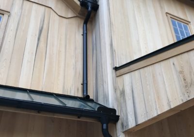 Black downspouts from the third floor tying into the second floor and onto the first floor.