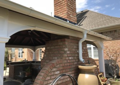White gutter system. Drops down into an water barrel that collects water.