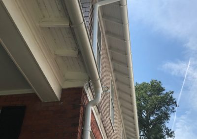 White gutters and downspouts. Second floor have exposed rafter tails to which the hangers are mounted.