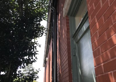 Another side of the church. Green side door. Anthracite metallic gutters and downspouts. Green leaves on tree bringing shade.