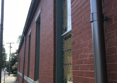 Church with red brick. Downspouts going into the sidewalk.
