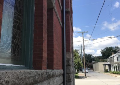 Side of church building. Red brick and anthracite metallic leader head and downspout.