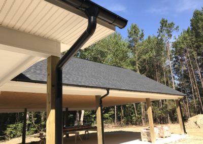 Black downspouts on every other post. Dark gray shingles and white trim and fascia.