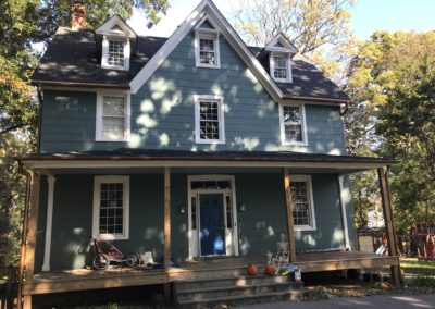 Copper metallic gutters. Three story home with green siding. Lots of trees.