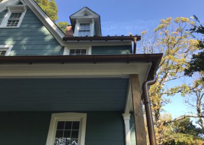 Copper metallic gutters and downspouts. Beautiful corner of the system and an overflow protector up high.
