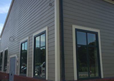 Green gutters and downspouts. Beige siding and red brick water table.