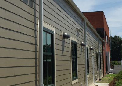 Lots of white gutter and downspouts on beige siding. The backside of an Altmeyer funeral home.